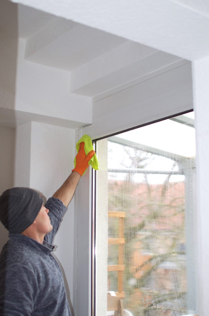 fensterreiniger-reinigt-fensterrahmen-mit-mikrofaserlappen