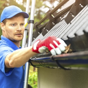 Dachrinnenreinigung-mit-Handschuhen-auf-einer-Teleskopleiter.