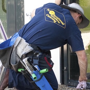 Ein-Fensterputzer-auf-den-Knien-wischt-die-Gummidichtung-einer-modernen-Glastuer-ab