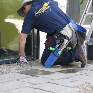 Ein-Fensterputzer-in-Suendersbuehl-Nbg-beugt-sich-tief-vor-um-eine-moderne-Glastuer-abzuwischen