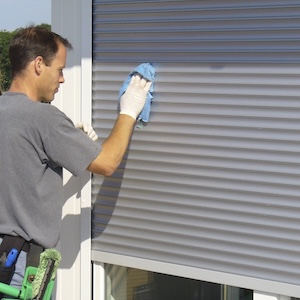 Ein-professioneller-Reinigungskraft-wischt-Fensterlaeden-mit-einem-feuchten-Mikrofasertuch-ab.